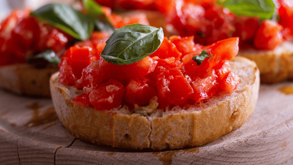 Bruschetta Toscana: pão italiano torrado, coberto com tomates frescos, manjericão e azeite de oliva, oferecendo uma entrada leve e cheia de sabor.